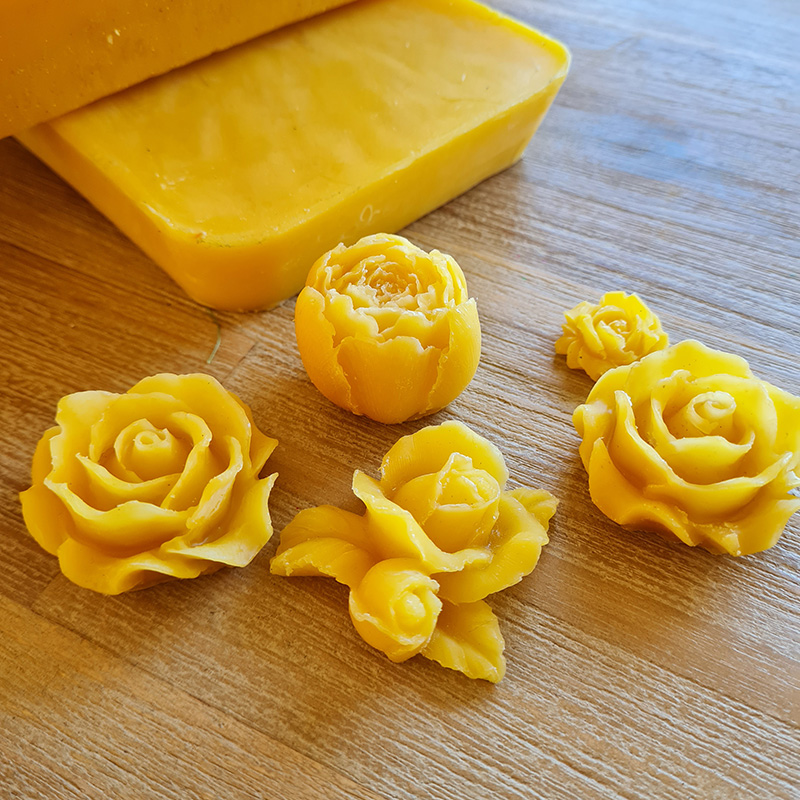 Plastic tub containing golden beeswax blocks with carved wax roses